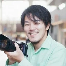 笑顔でカメラを構える横田裕市氏のポートレート
